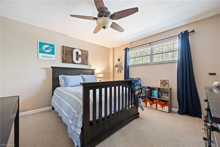 Carpeted bedroom featuring ceiling fan and baseboards