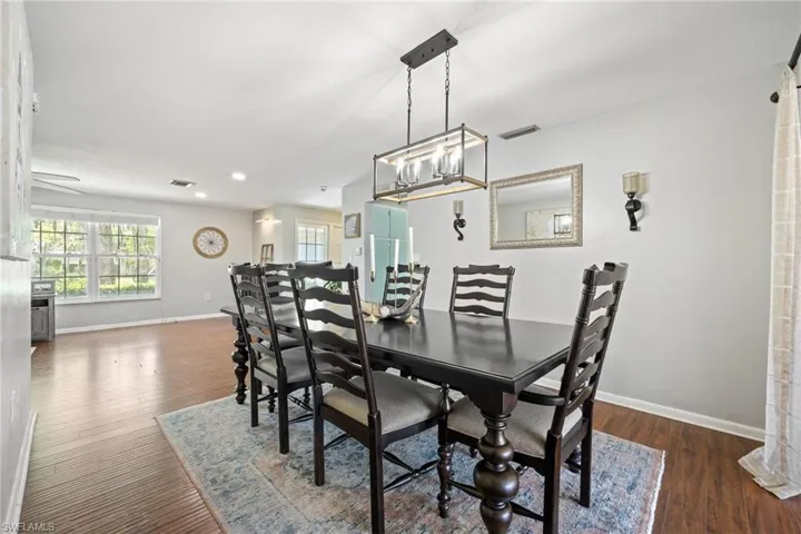 Dining room featuring baseboards, a chandelier, visible vents, and wood finished floors