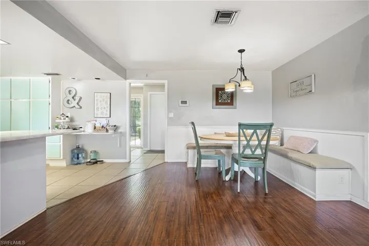 Dining space with visible vents, a wainscoted wall, and wood finished floors