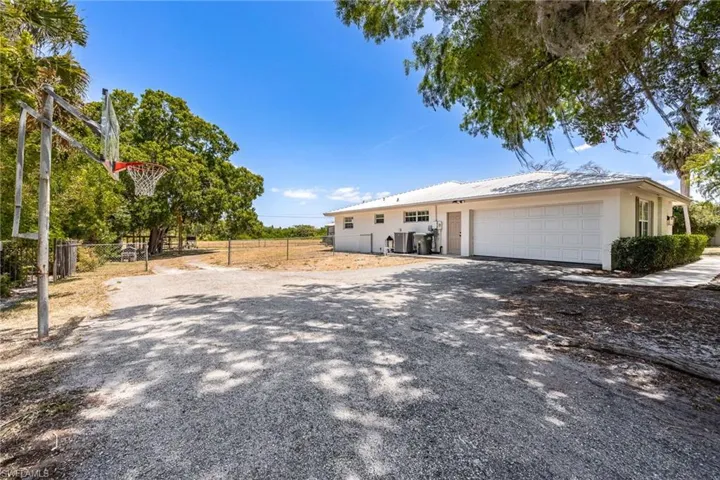 View of front facade with fence, a garage, stucco siding, and driveway