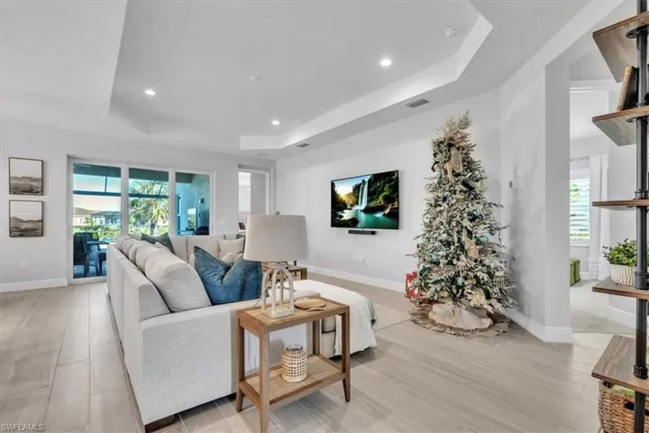 Living room with a raised ceiling, recessed lighting, and light wood-style flooring
