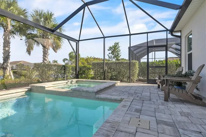Outdoor pool featuring a sunroom, glass enclosure, a patio, and an in-ground hot tub