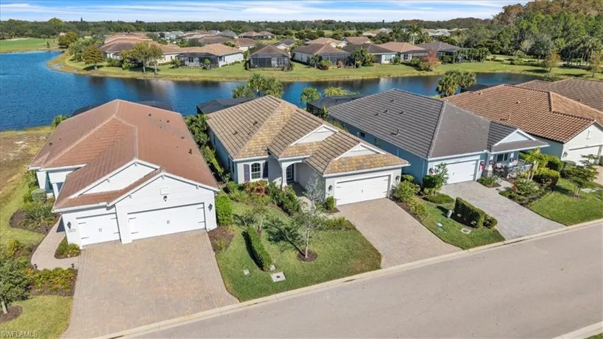 Aerial perspective of suburban area featuring a large body of water and a tree filled landscape