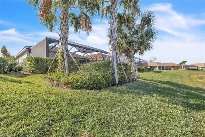 View of grassy yard with a lanai and a sunroom