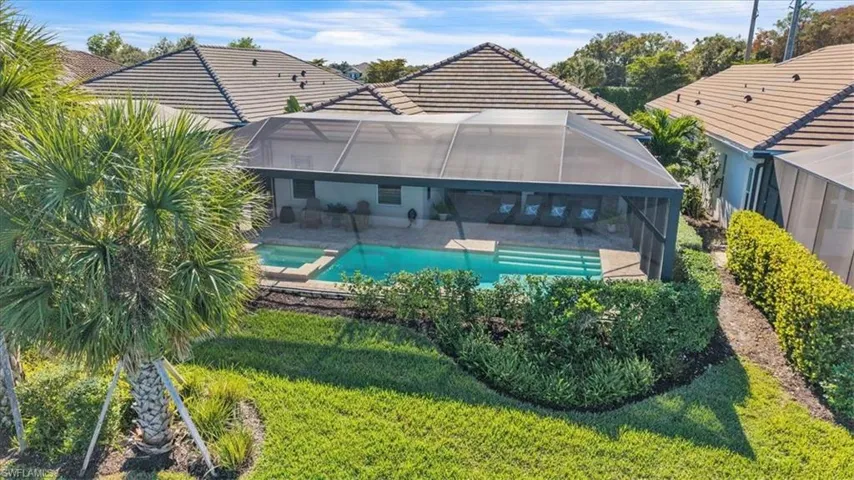 Rear view of house with a sunroom, a pool with connected hot tub, glass enclosure, a tile roof, and a patio