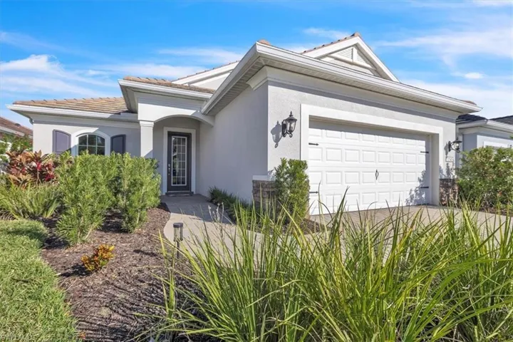 View of front of home with stucco siding, an attached garage, a tiled roof, and driveway
