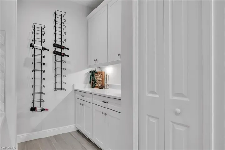 Bar with white cabinetry and light stone counters
