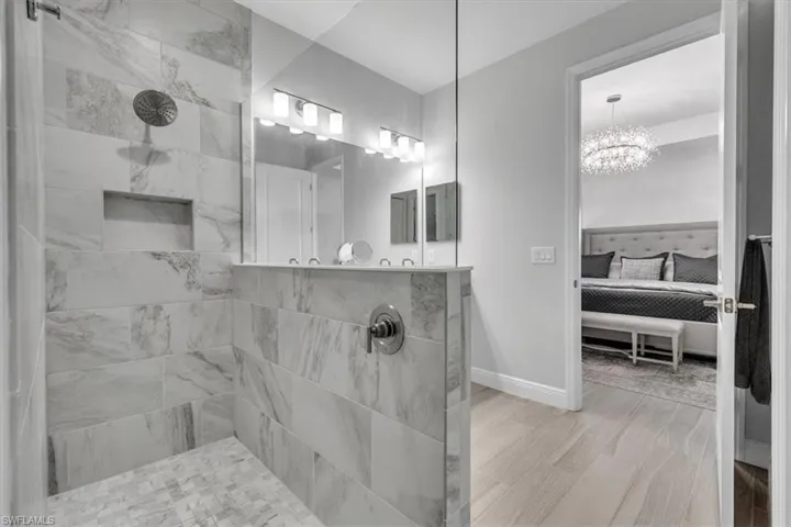 Bathroom featuring connected bathroom, a walk in shower, a chandelier, and light wood-style floors