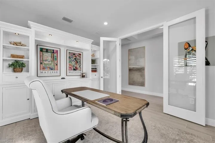 Office space with light wood-style flooring, built in shelves, and recessed lighting