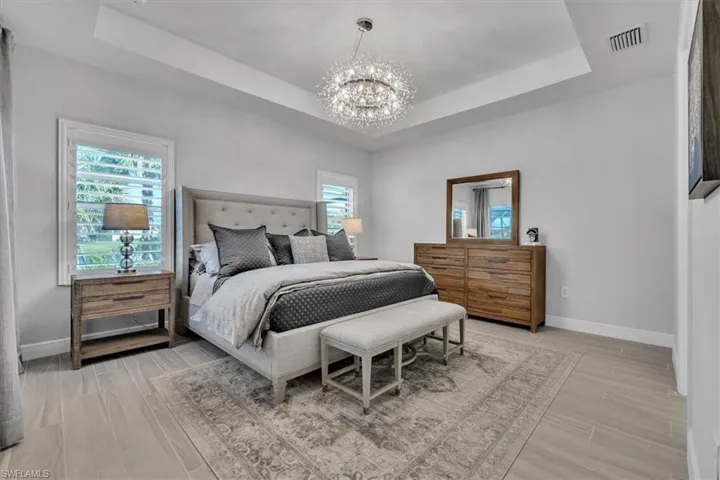 Bedroom featuring wood tiled floors, a chandelier, and a tray ceiling