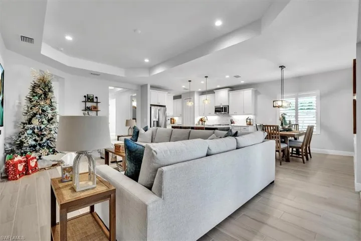 Living area with a tray ceiling, wood tiled floors, and recessed lighting