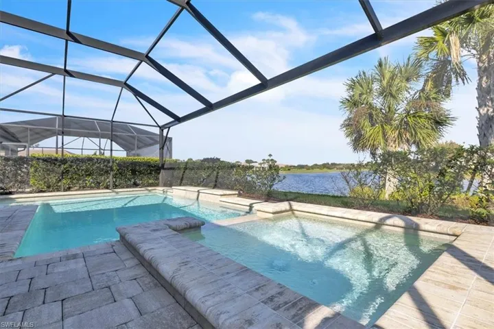 View of swimming pool featuring a lanai, a water view, a pool with connected hot tub, and a sunroom