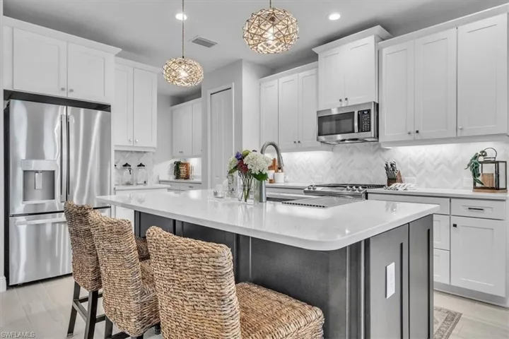 Kitchen with appliances with stainless steel finishes, hanging light fixtures, a center island with sink, white cabinetry, and recessed lighting