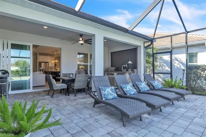 View of patio featuring glass enclosure, a sunroom, ceiling fan, and grilling area