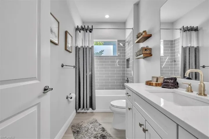 Full bath featuring shower / bath combo with shower curtain, vanity, and wood finish floors