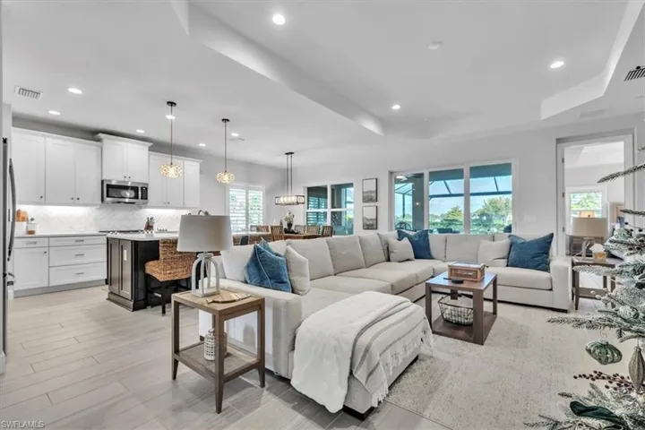 Living area featuring recessed lighting, a tray ceiling, and light wood-style flooring