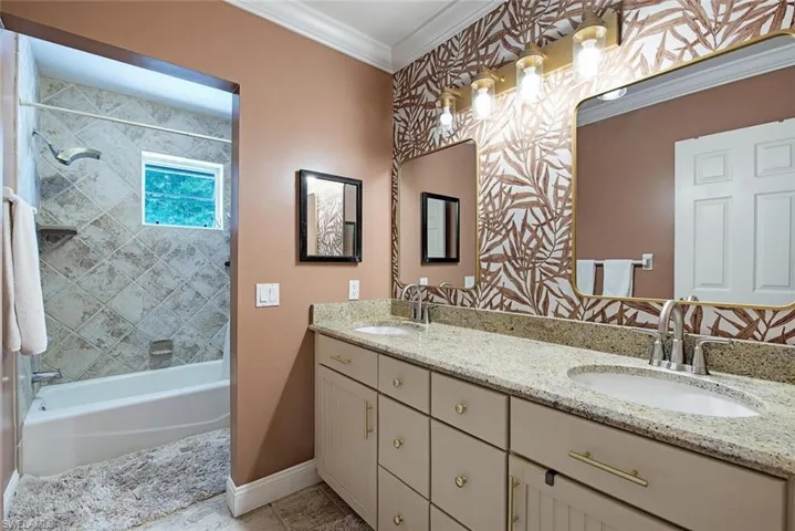 Guest bathroom featuring shower / wash tub combination, crown molding, and double vanity