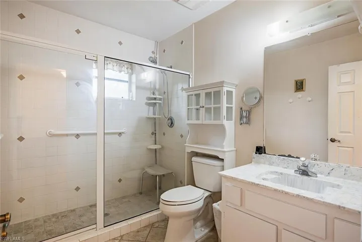 Full bath with a shower stall, vanity, and light tile patterned flooring