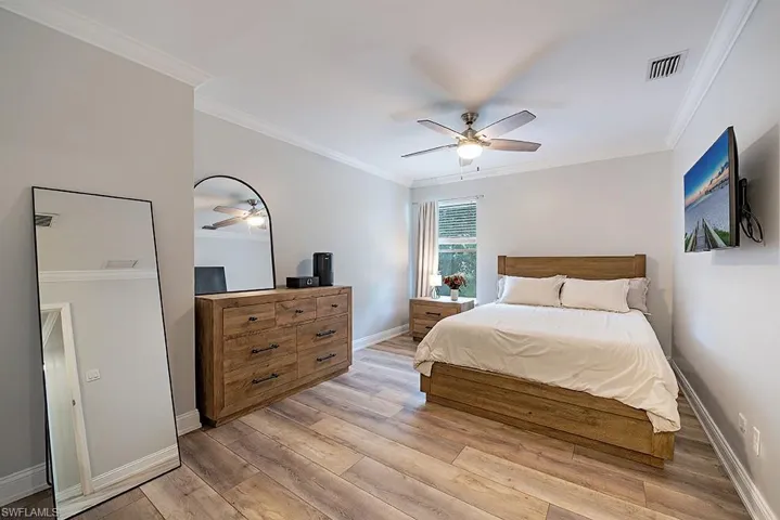 Guest Bedroom with crown molding, light wood-style flooring, and a ceiling fan