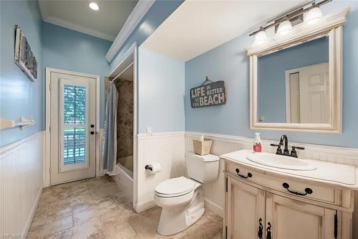 Pool Bath and Guest bath with crown molding, vanity, shower / bath combo, and wainscoting
