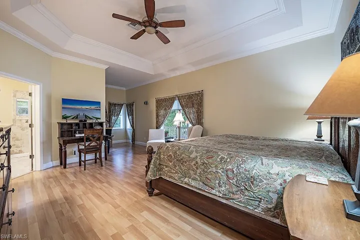 Master Bedroom with a raised ceiling, light wood-type flooring, sitting area, ornamental molding, and ceiling fan