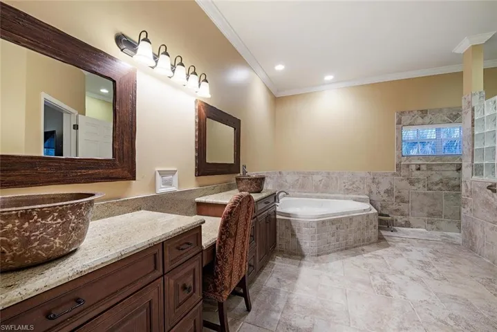Master Bathroom featuring two vanities, a garden tub, crown molding, and recessed lighting