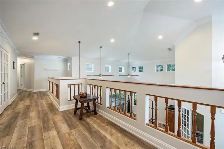 Hall/Loft featuring crown molding, healthy amount of natural light, vaulted ceiling, recessed lighting, and wood finished floors