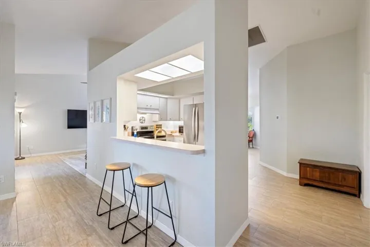 Kitchen with appliances with stainless steel finishes, white cabinetry, a kitchen breakfast bar, kitchen peninsula, and light wood-type flooring
