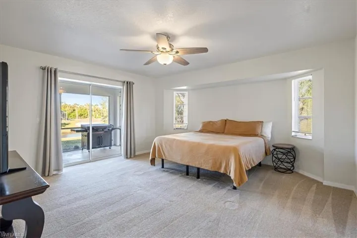 Bedroom with access to exterior, light carpet, multiple windows, and a textured ceiling