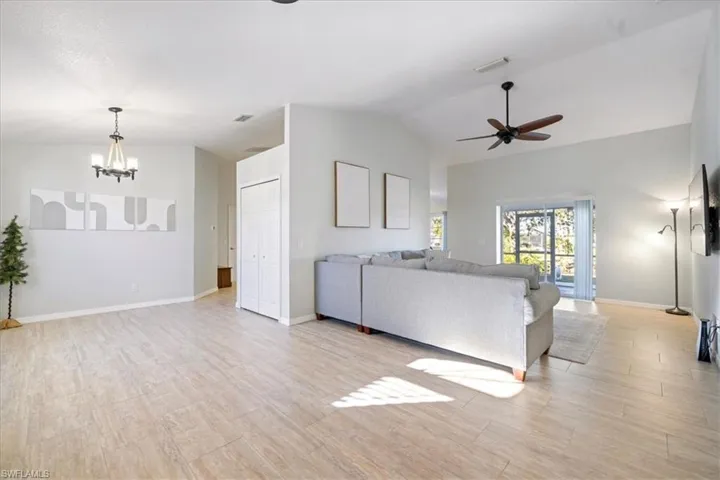 Unfurnished living room featuring lofted ceiling, light hardwood / wood-style floors, and ceiling fan with notable chandelier