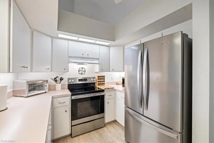 Kitchen featuring light wood-type flooring, white cabinets, and appliances with stainless steel finishes