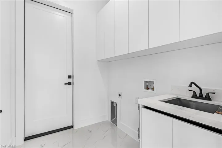 White flat-panel cabinetry, white engineered stone countertop, undermount sink, matte black faucet, and white tile flooring