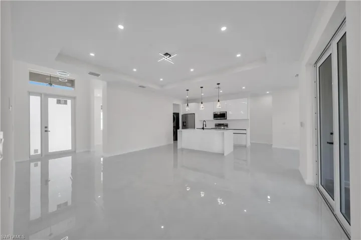 Unfurnished living room featuring a raised ceiling and recessed lighting