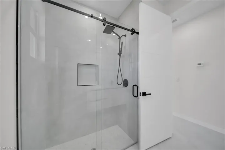 Full bath with a shower stall and concrete flooring