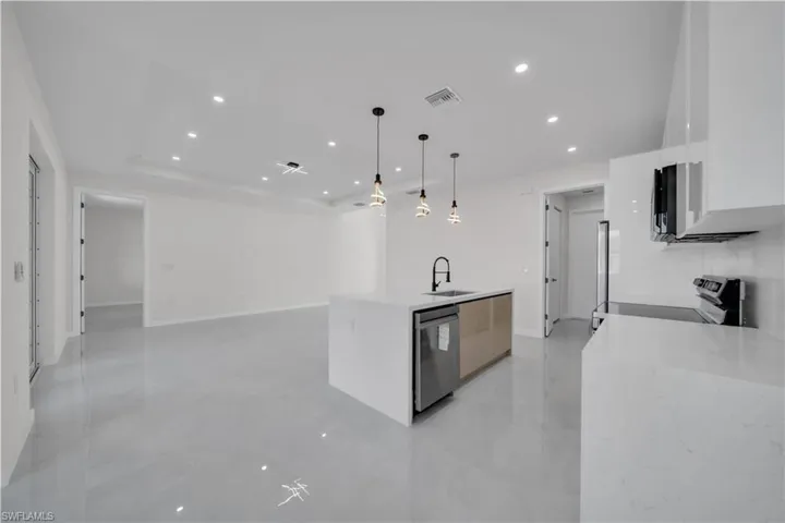 Kitchen featuring a kitchen island with sink, light stone counters, open floor plan, and modern cabinets