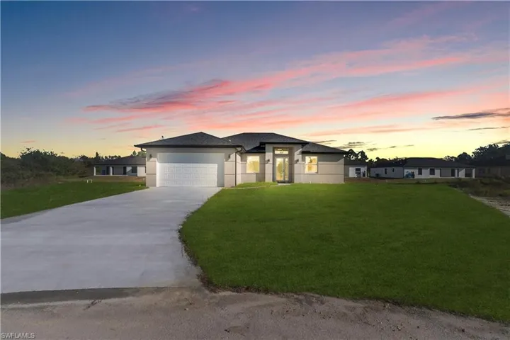 Prairie-style home with a front yard, a garage, driveway, and stucco siding