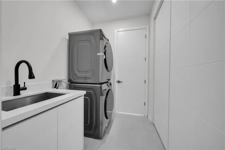 Laundry area featuring stacked washer and dryer and cabinet space