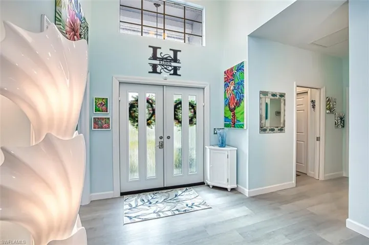 Foyer entrance featuring a towering ceiling, light hardwood / wood-style flooring, and french doors