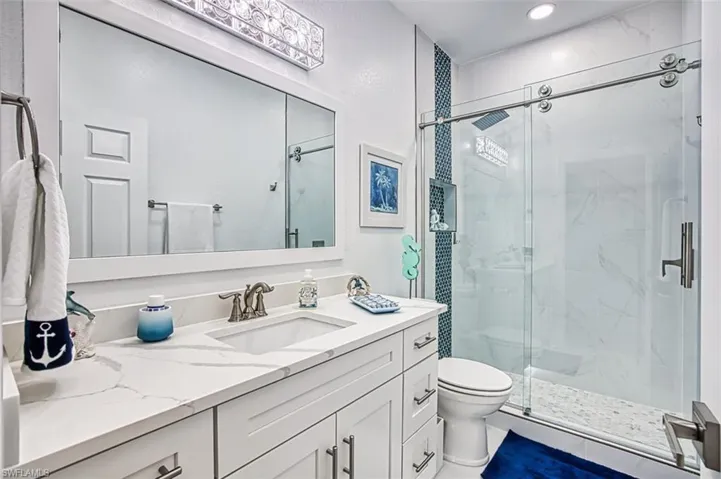 Bathroom featuring tile patterned flooring, walk in shower, vanity, and toilet