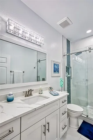 Bathroom with vanity, toilet, tile patterned floors, and a shower with shower door