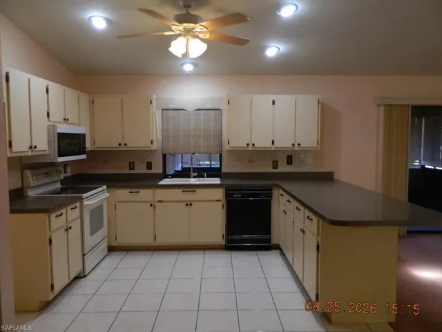 Kitchen featuring white cabinetry, dark countertops, white tile flooring, recessed lighting, and a ceiling fan