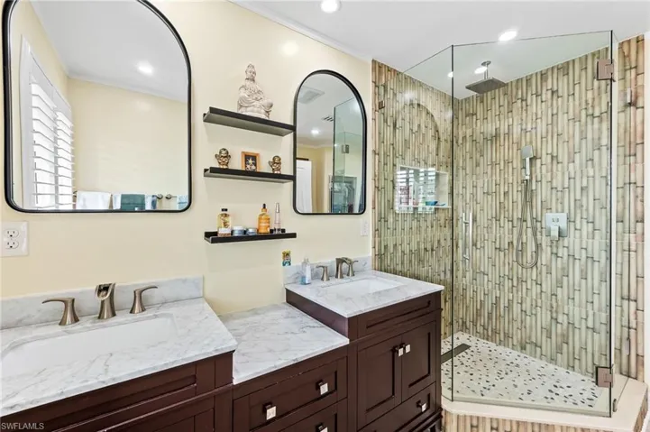 Full master bathroom featuring a stall shower, double vanity, crown molding, and recessed lighting