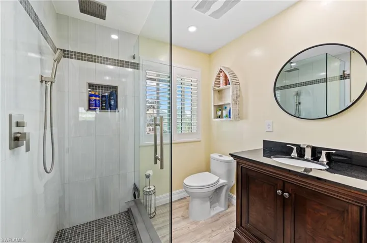 Full guest bath with vanity, a glass shower stall, and light wood-style flooring