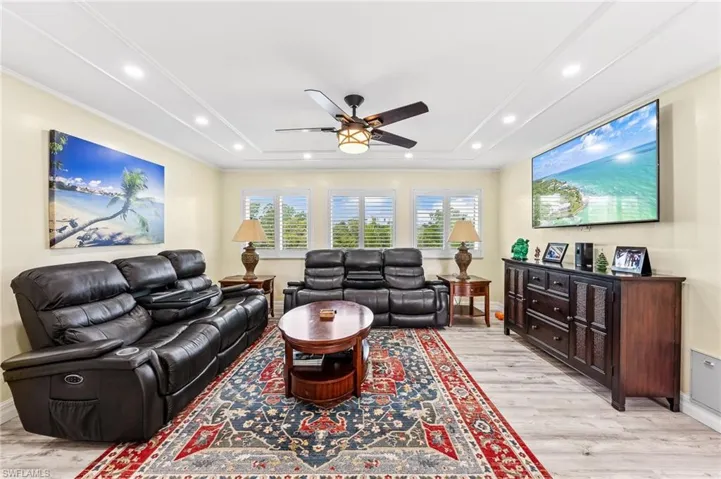 Living room featuring light wood-style floors, crown molding, tray ceiling, and recessed lighting
