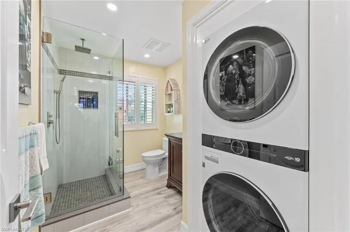 Build-in washer / dryer combo in guest bathroom, light wood-style flooring, and recessed lighting
