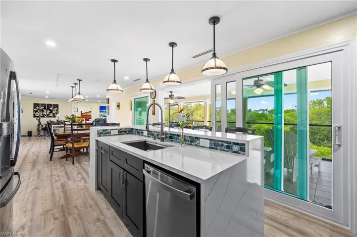 Kitchen featuring dark cabinetry, pendant lighting, stainless steel appliances, light stone countertops, and recessed lighting