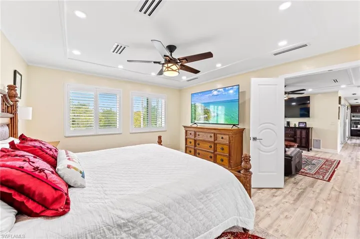 Awesome waterfront views from Master Bedroom featuring light wood finished floors, a ceiling fan, recessed lighting, and crown molding