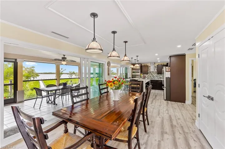 Endless water view from the dining space featuring light wood-style flooring, ornamental molding, recessed lighting, and ceiling fan