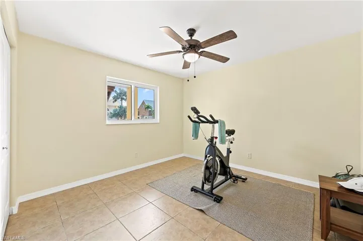 Exercise area or 2nd bedroom at lower level featuring ceiling fan and light tile patterned flooring