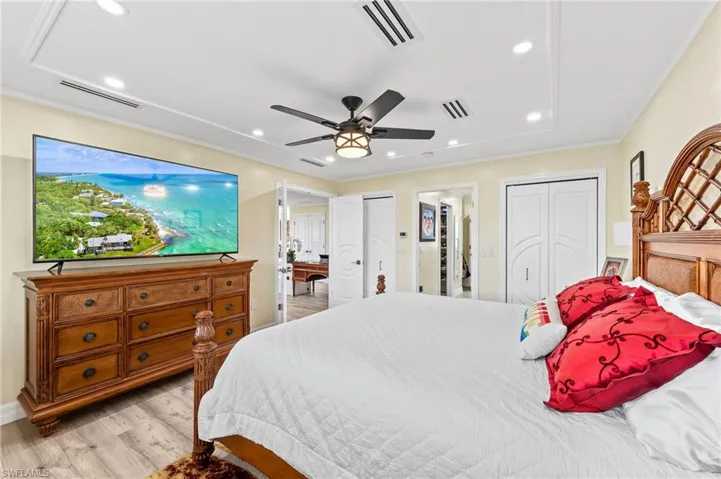 Double doors to Master Bedroom with light wood-type flooring, two closets, a ceiling fan, recessed lighting, and ornamental molding